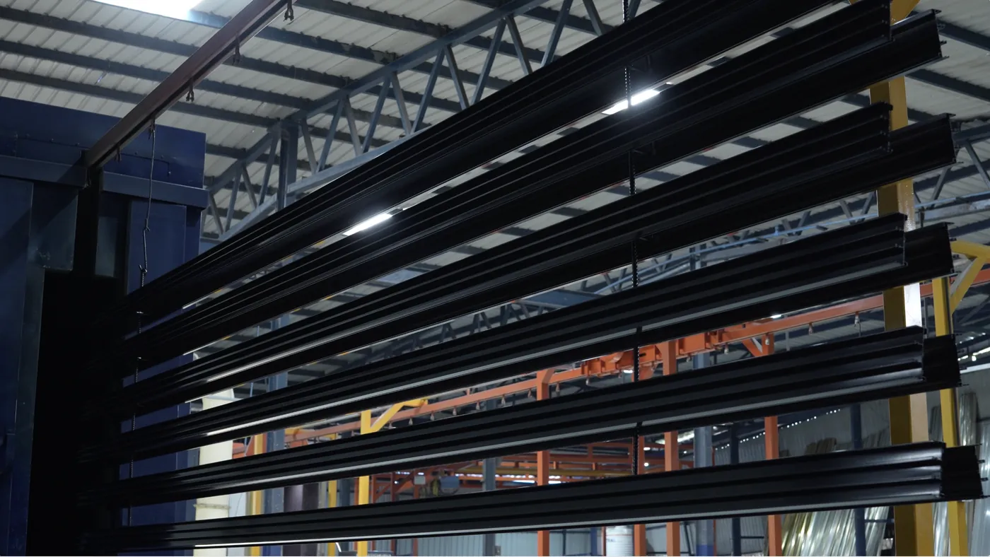 Black powder-coated aluminium sections hanging in rows after coating