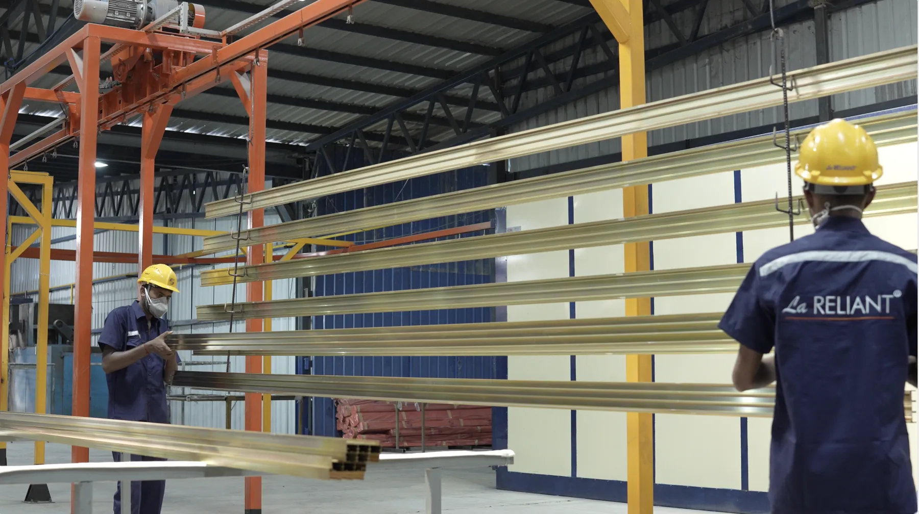 Profiles hanging on the automatic powder coating line, with operators at work