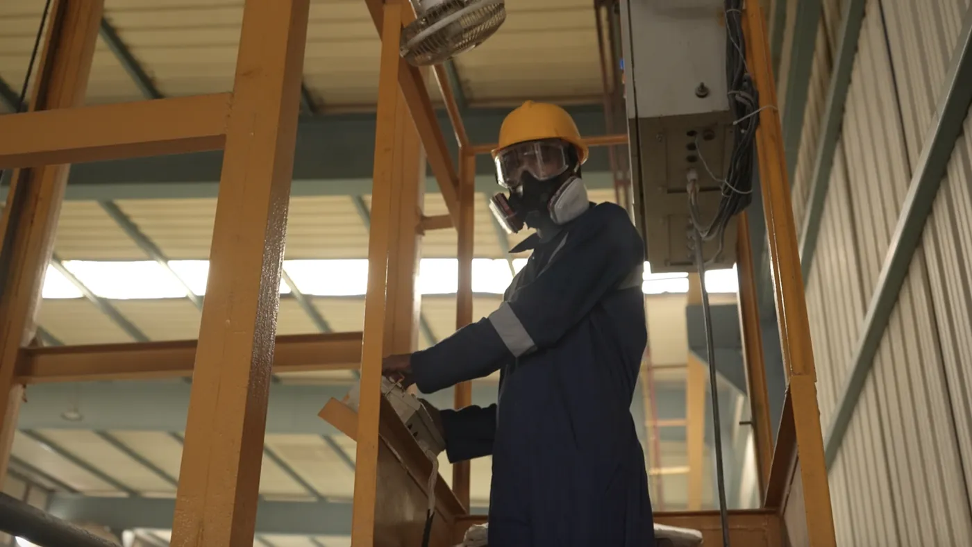 Operator in respiratory protection beside the automatic anodizing line